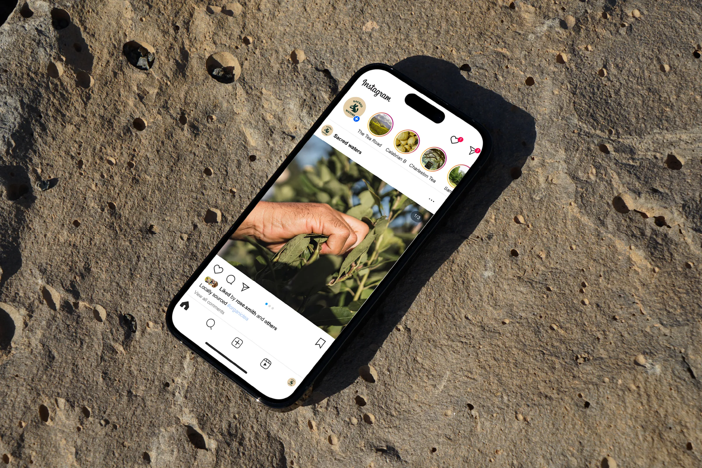 Phone on a rock showing the Sacred Waters Instagram profile
